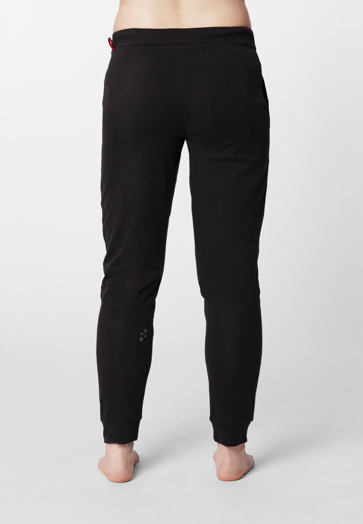 Rückansicht einer Frau in einer Pyjamahose in der Farbe „night black“.