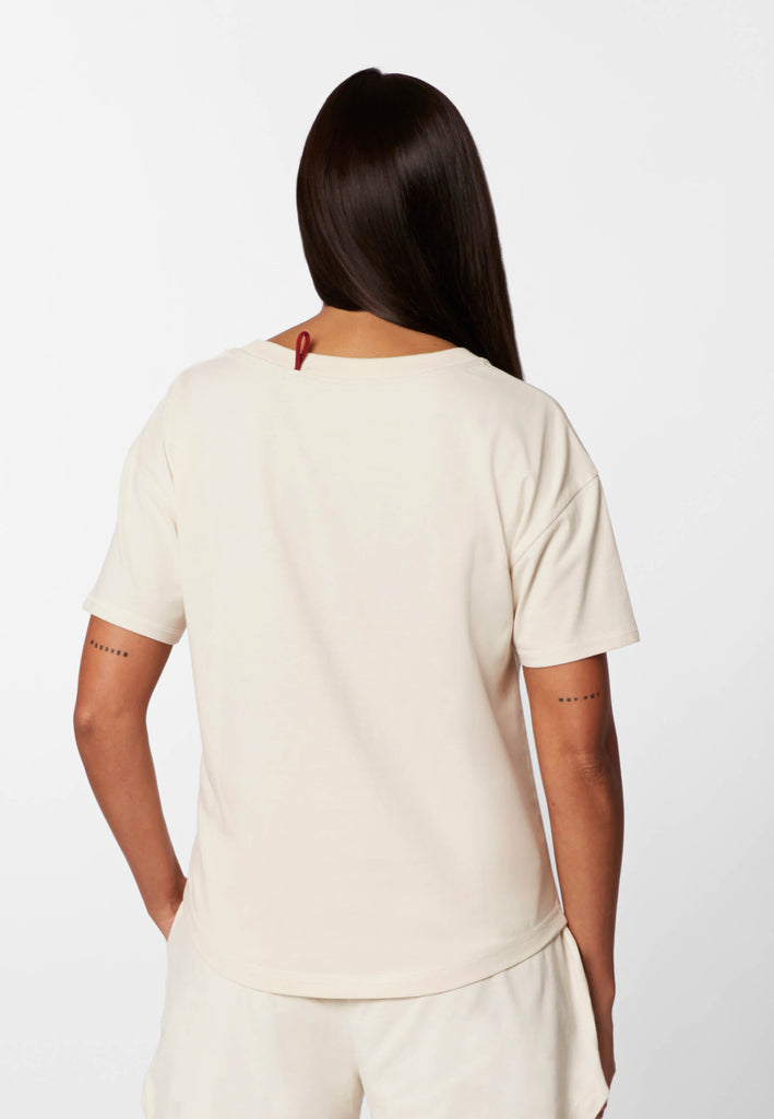 Rückansicht einer Frau im Pyjama T-Shirt in der Farbe „moon white“.