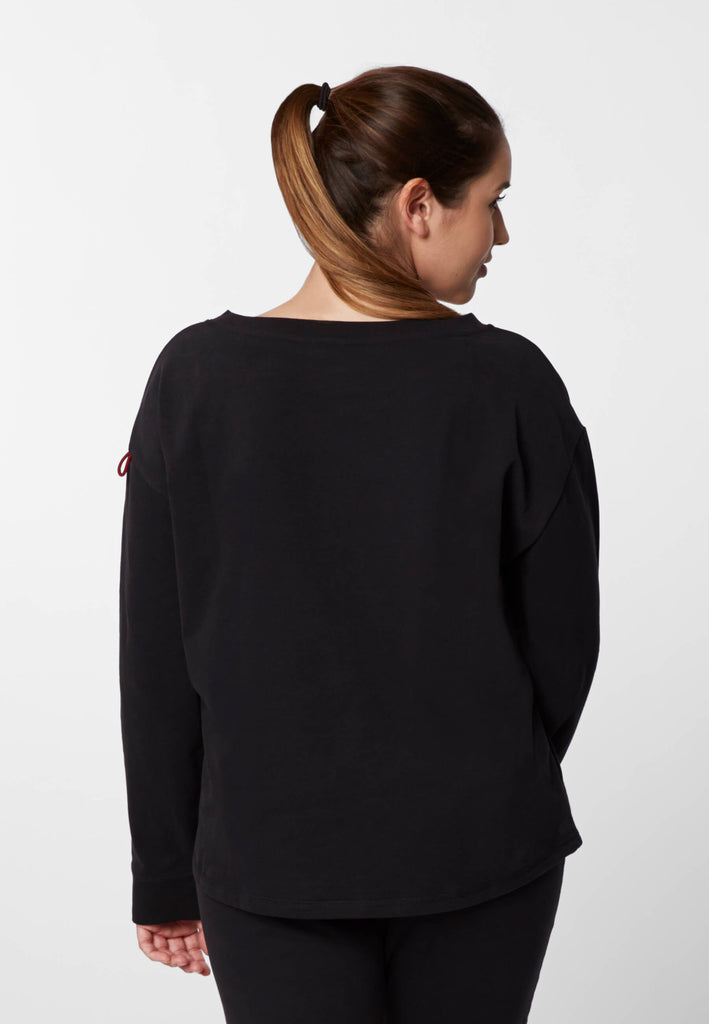 Rückansicht einer Frau im Pyjama Longsleeve in der Farbe „night black“.