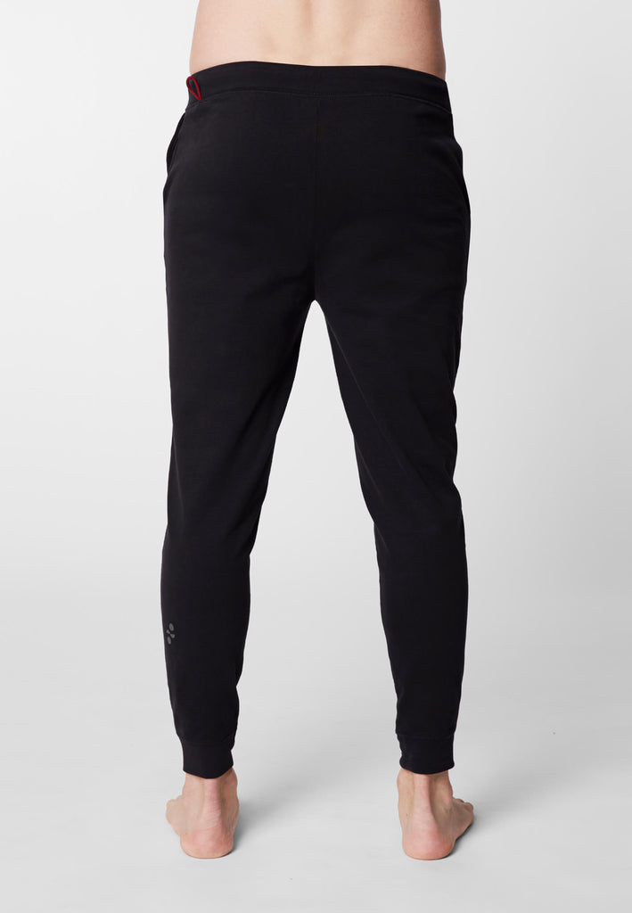 Rückansicht eines Mannes in einer Pyjamahose in der Farbe „night black“.