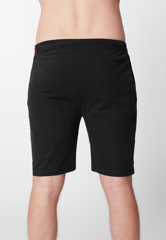 Detail Rückansicht eines Mannes in einer Pyjama Shorts in der Farbe „night black“.