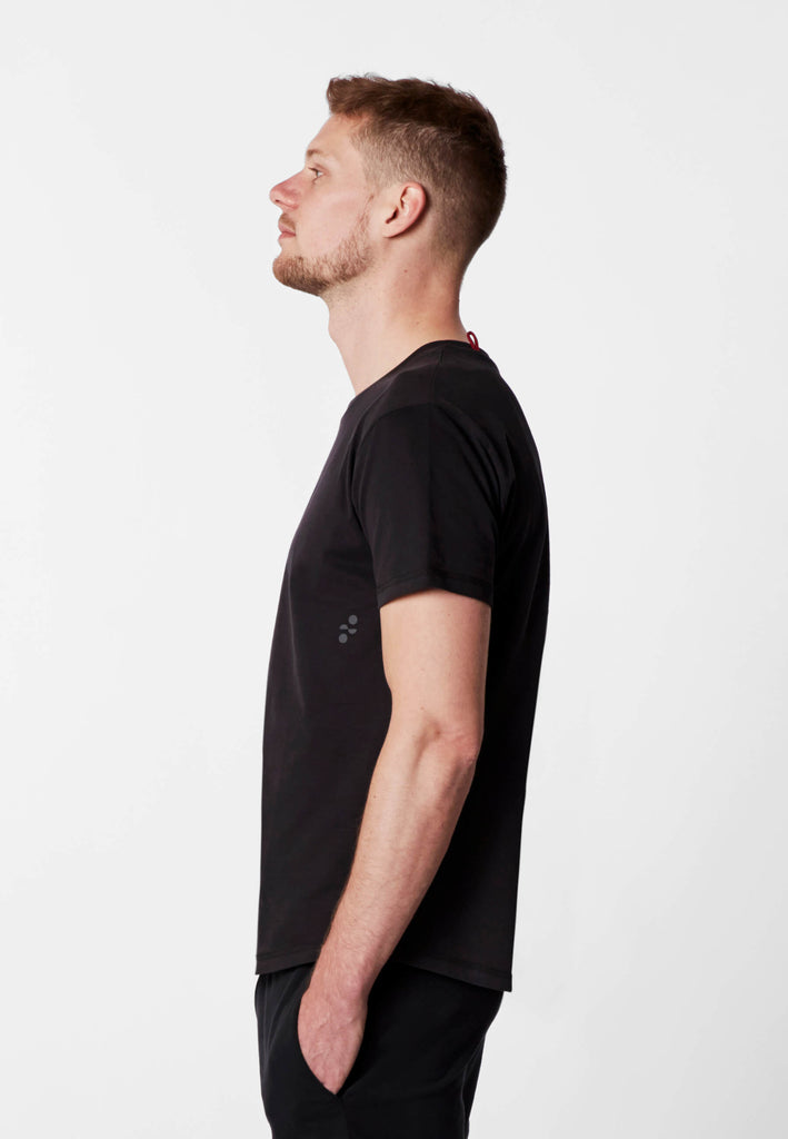 Seitenansicht eines Mannes im Pyjama T-Shirt in der Farbe „night black“.