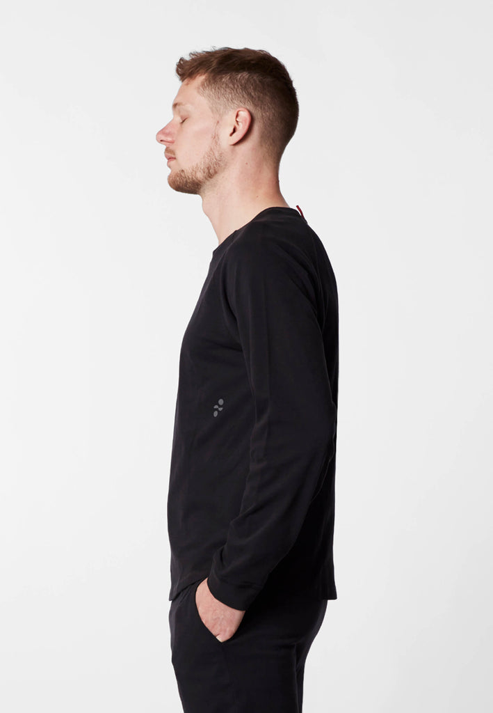Seitenansicht eines Mannes im Pyjama Longsleeve in der Farbe „night black“.