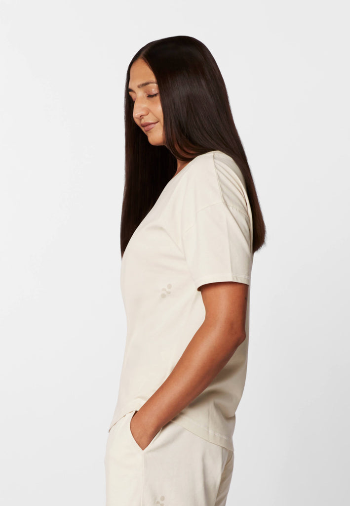 Seitenansicht einer Frau im Pyjama T-Shirt in der Farbe „moon white“.