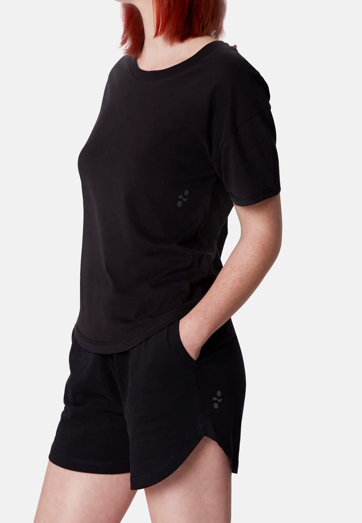 Seitenansicht einer Frau im Pyjama T-Shirt in der Farbe „night black“.