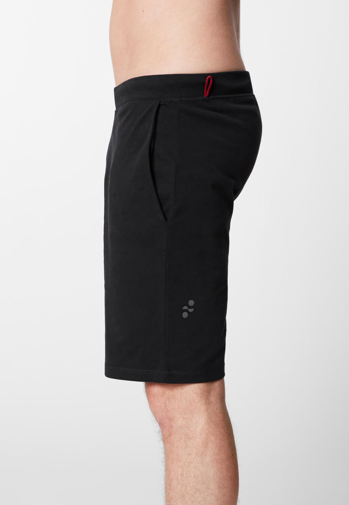 Detail Seitenansicht eines Mannes in einer Pyjama Shorts in der Farbe „night black“.