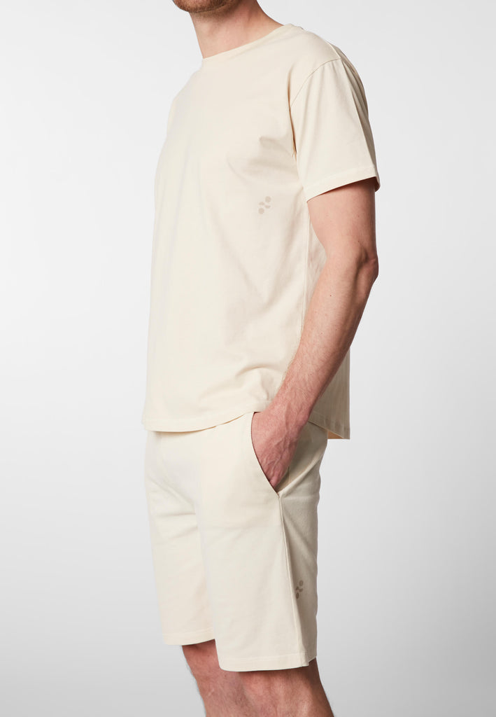 Detailbild Seitenansicht eines Mannes im Pyjama T-Shirt in der Farbe „moon white“.