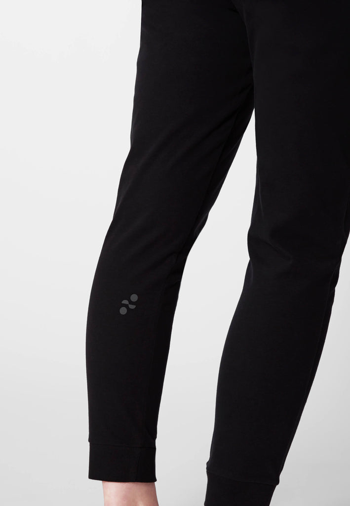 Detailbild vom Logo-Print am Wadenbein im Ton-in-Ton Kontrast auf dem Baumwollstoff in der Farbe „night black“.