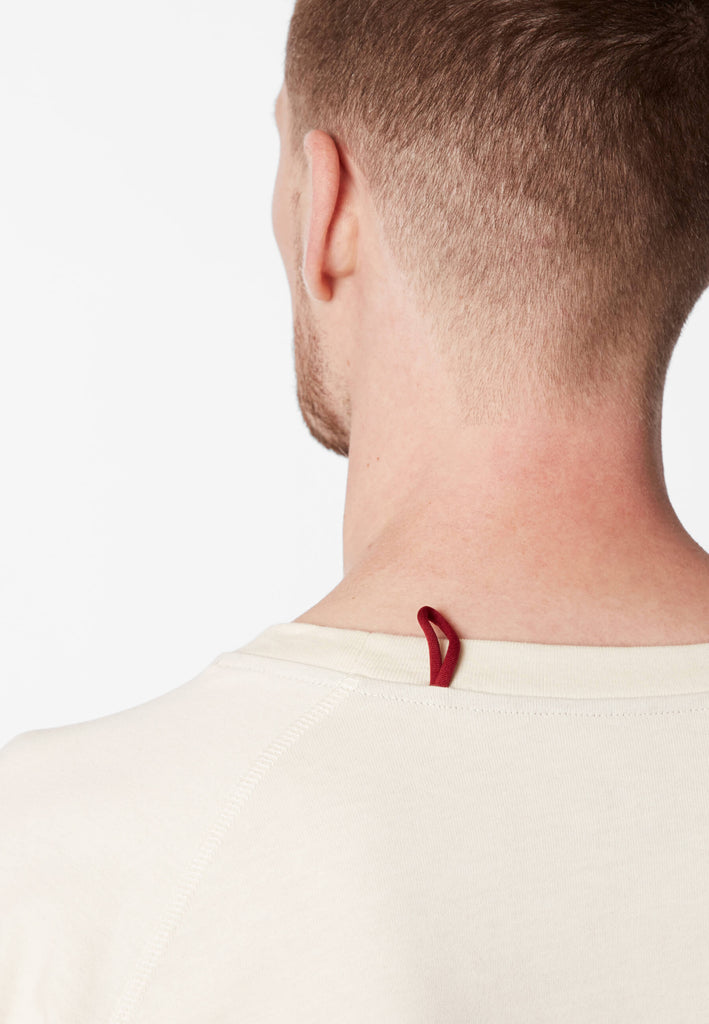 Detailbild einer roten Schlaufe am Pyjama Longsleeve in der Farbe „moon white“ an der Nackennaht.