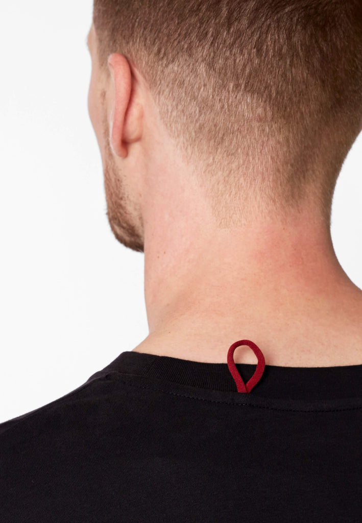 Detailbild einer roten Schlaufe am Nachthemd in der Farbe „night black“ an der Nackennaht.