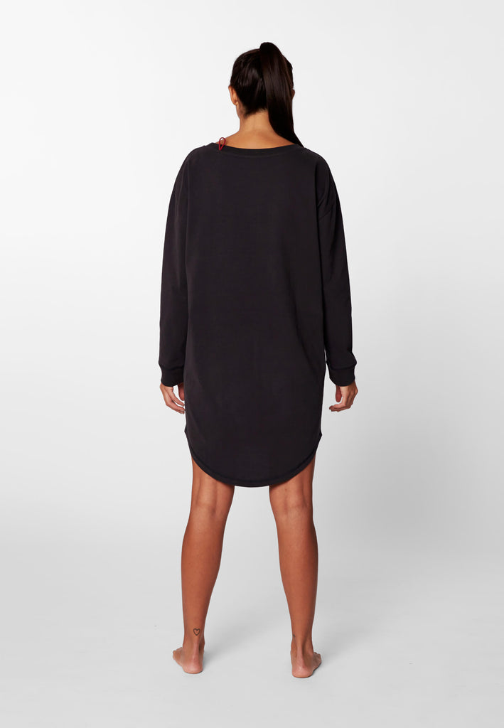 Rückansicht einer Frau im langarm Nachthemd in der Farbe „night black“.