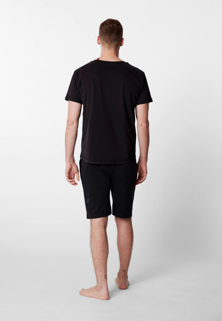 Ganzkörper Rückansicht eines Mannes im Pyjama T-Shirt und Pyjama Shorts in der Farbe „night black“.