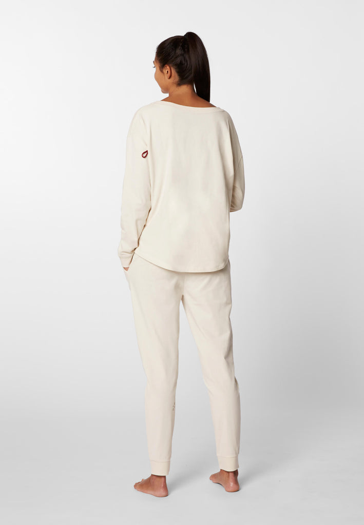 Ganzkörper Rückansicht einer Frau im Pyjama Longsleeve und Pyjamahose in der Farbe „moon white“.