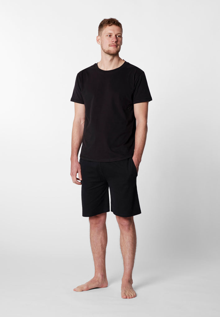 Ganzkörper Vorderansicht eines Mannes im Pyjama T-Shirt und Pyjama Shorts in der Farbe „night black“.