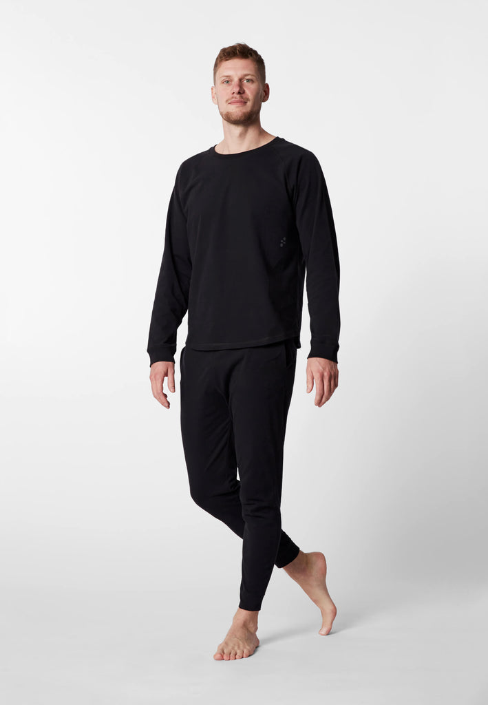 Ganzkörper Vorderansicht eines Mannes im Pyjama Longsleeve und Pyjamahose in der Farbe „night black“.