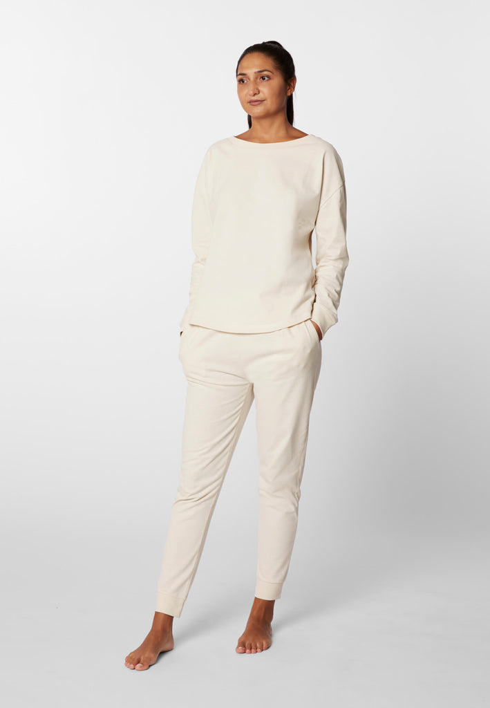 Ganzkörper Vorderansicht einer Frau in einer Pyjamahose und eines Pyjama Longsleeves in der Farbe „moon white“.