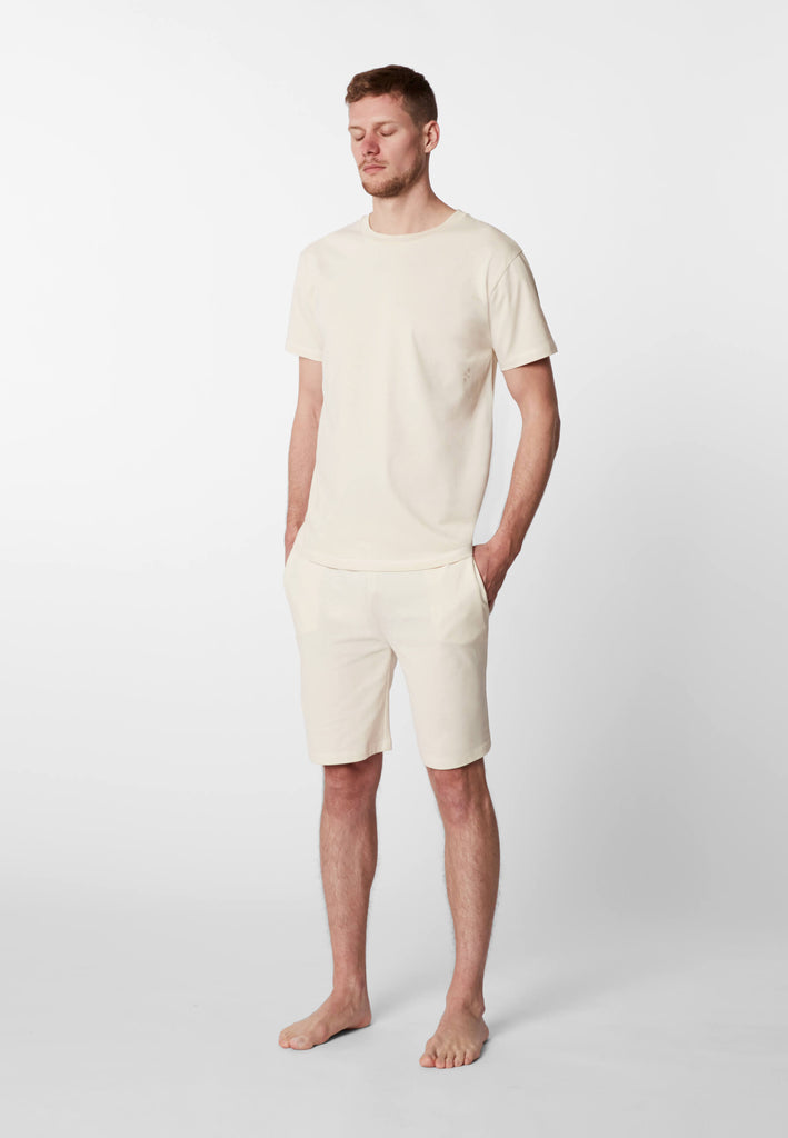 Ganzkörper Vorderansicht eines Mannes in einer Pyjama Shorts und einem Pyjama T-Shirts in der Farbe „moon white“.