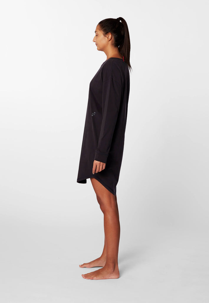 Seitenansicht einer Frau im langarm Nachthemd in der Farbe „night black“.