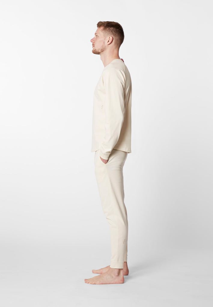 Ganzkörper Seitenansicht eines Mannes im Pyjama Longsleeve und Pyjamahose in der Farbe „moon white“.